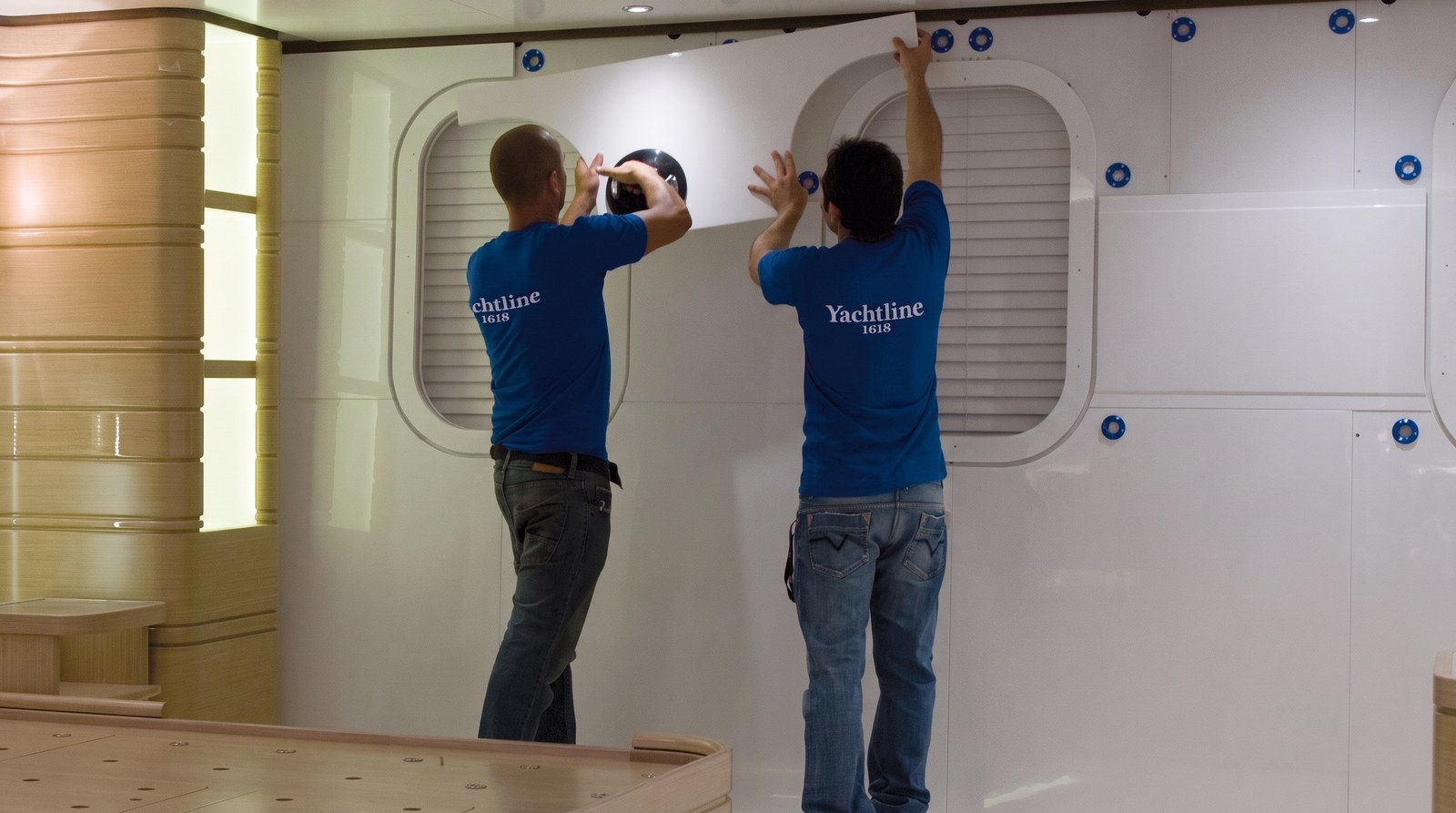 Dos instaladores fijando un panel blanco en el interior de un yate